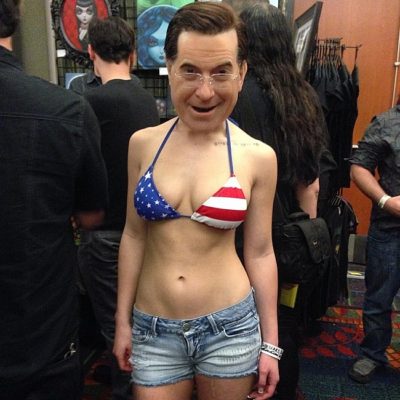 Woman dressed as Stephen Colbert, but looks like a bobble head.